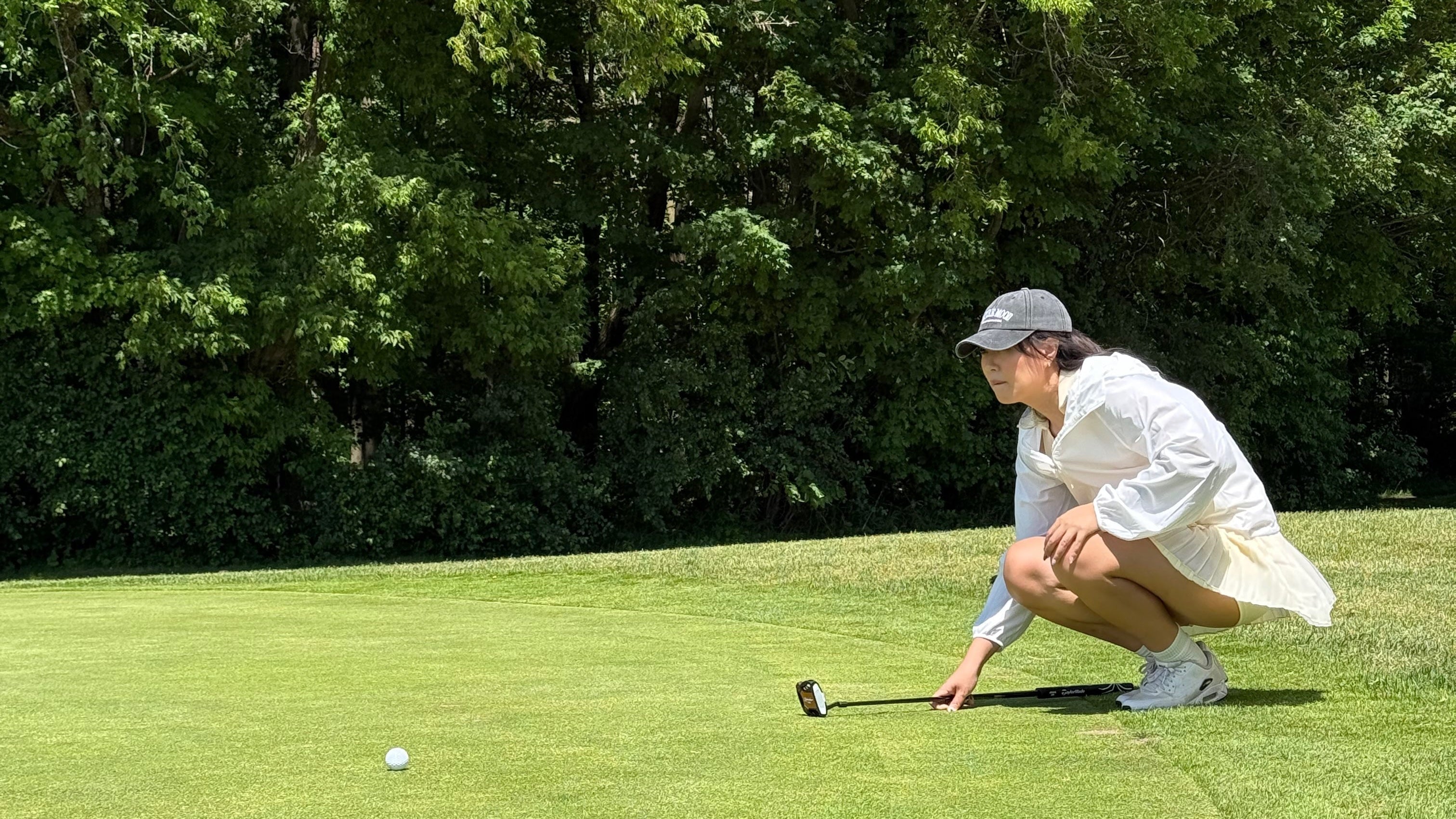 Person on a golf course preparing to take a shot with trees in the background